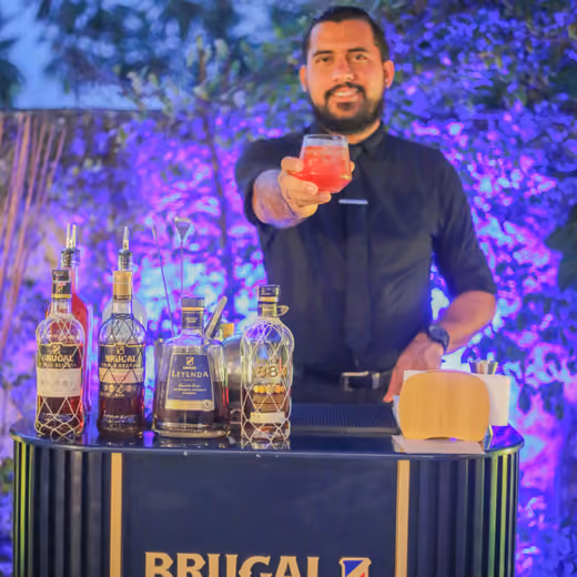 Bartender ofreciendo un cóctel junto a las botellas de ron