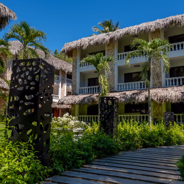 Edificios de Tribe Resorts con techos de cana entre jardines