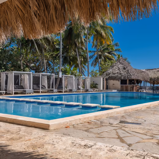 Piscina con camas balinesas y palmeras