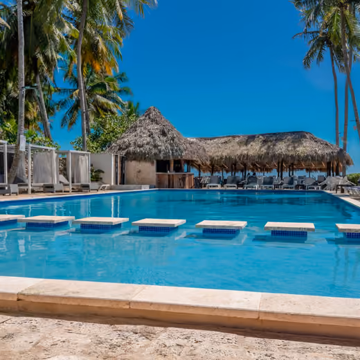 Piscina con palmeras y cabañas